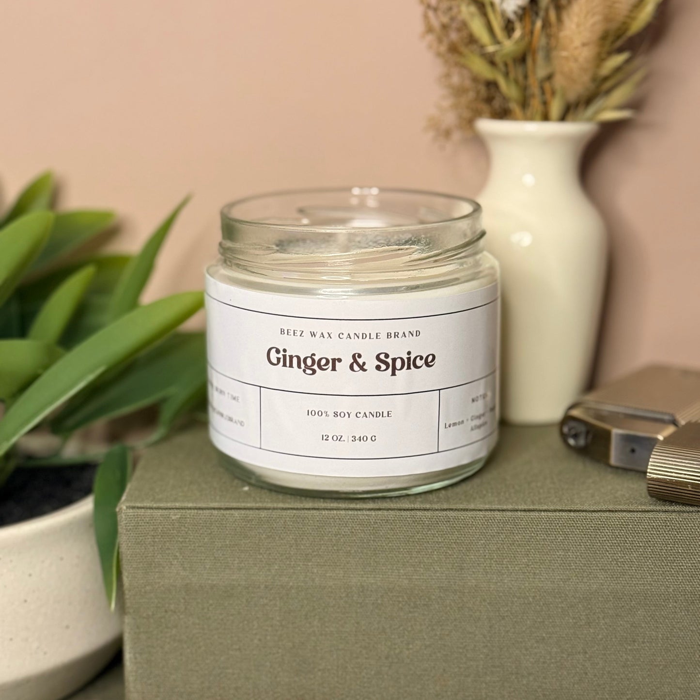 Ginger & Spice candle on a green box with plants and a vase in the background