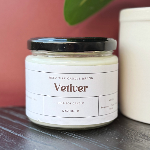 Jar of Vetiver scented candle with a black lid on a wooden surface.